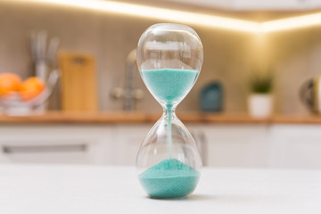 Closeup of hourglass on a white wooden table with defocus kitchen