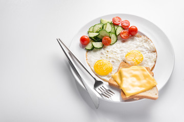 Plate of fried eggs and fresh vegetables, cheese toast