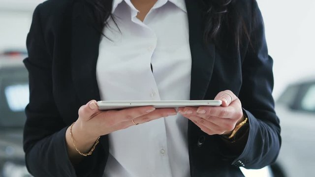 Image for graphic implements. Close-up girl in a suit holds a tablet and presses on it with a finger