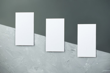 ockup of a three business cards placed vertically with shadows on a gray background. White card on grunge background, concrete. Top of view.