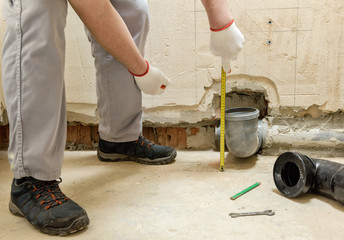 A worker is measuring the sewage drain pipe.