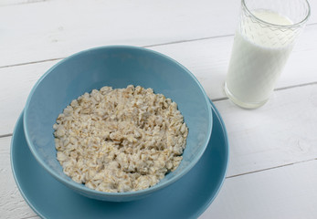 Plate with tasty oatmeal and banana slices on white wood background. Concept image of breakfast, healthy eating.