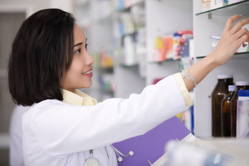 female pharmacies are checking current drugs on the shelves in the store
