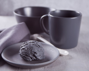 Black ice cream on a black ceramic plate with gray napkin on a gray table