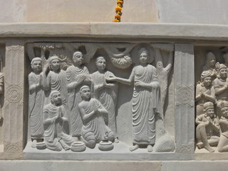 stone carved wall art of Buddha teaching or preaching to his followers on the stupa, in Mahabodhi Vihara or temple and monastery