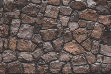 Stone mosaic, brown masonry. Old stone wall surface, brown stone texture, background. Rocks, bricks building's facade. Pattern of dirty shabby rocks.