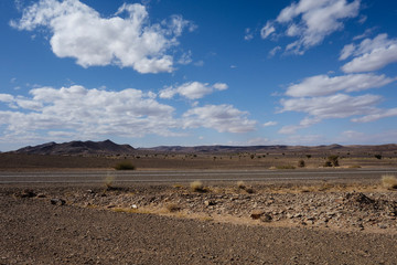 Moroccan highway featuring a rocky desert landscape on a road-trip from Marrakesh to Merzouga, Morocco