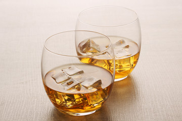 Two glasses with whiskey with ice cubes