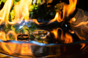 Gold ring on glass with fire in the background.
