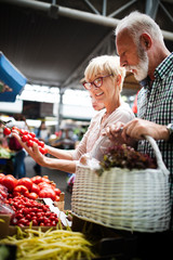 Shopping, food, sale, consumerism and people concept - happy senior couple buying fresh food