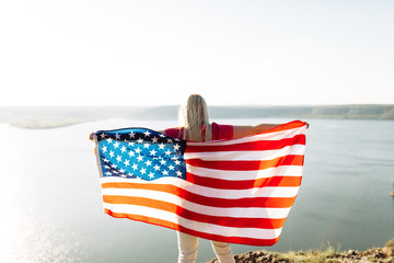 Patriotic holiday. Young woman holding USA flag.