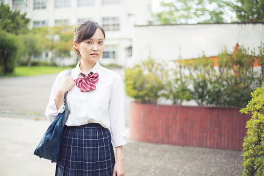 校門の前に立つ女子高生