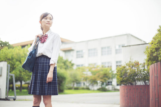 校門の前に立つ女子高生