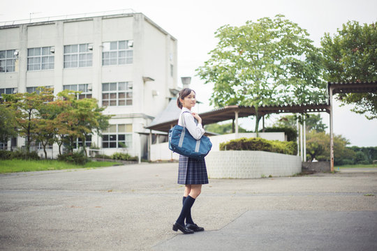 校舎の前に立つ女子高生