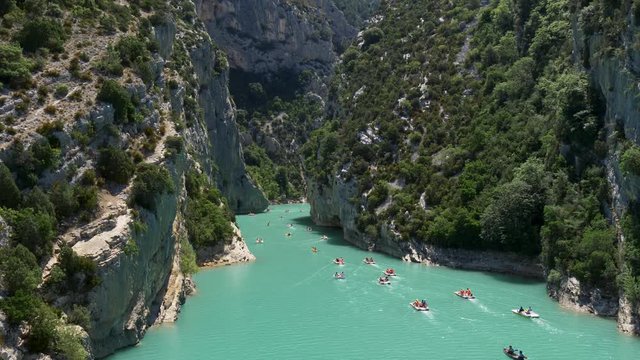 People sailing on pedal boats at the Verdon Gorge between Alps mountains in Provence, France. Waters of Verdon River have startling turquoise-green color. Aerial shot, UHD