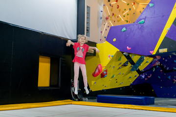 sporty girl rock climber on the climbing wall and trampoline