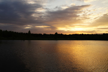 Bright sunset on a forest lake. Silence in the evening.