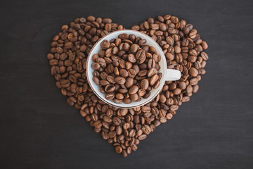 A cup with coffee beans. White tea pair with coffee beans. Heart of coffee.