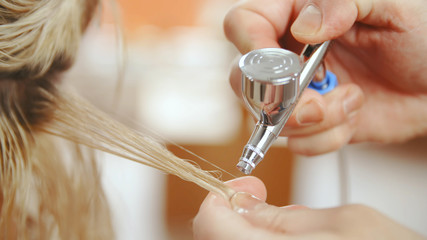 Spraying blonde hair with airbrush close-up