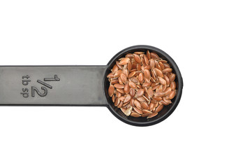 Leinsamen in Dosierlöffel auf weißem Hintergrund