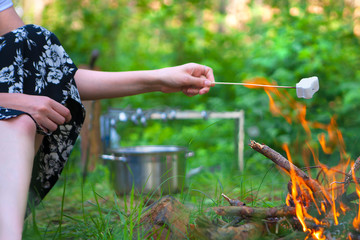Woman roasting marshmallows over a campfire. Toasted marshmallows open flame on skewer