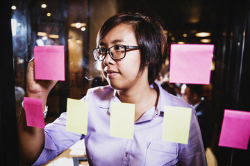 close up asian businesswoman writing a plan on sticky notes