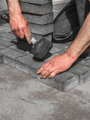 Mason is building pavement. Men hands lays layers of bricks.