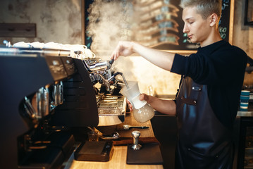 Male barista prepares cappuccino on coffee machine