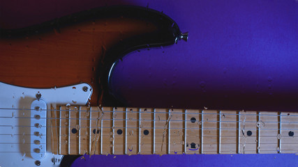 electric guitar behind the glass with water drops . color background