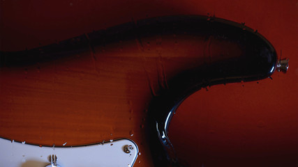 electric guitar behind the glass with water drops . color background