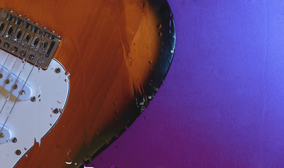 electric guitar behind the glass with water drops . color background