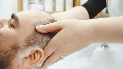 Applying shampoo on male head in sink