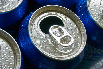 Close up of blue soda cans with open pull tab and condensation or water drops    