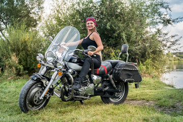 Fototapeta premium Beautiful young woman posing with motorcycle outside