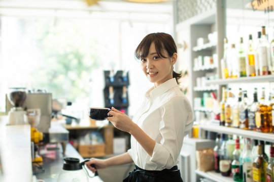 コーヒーを提供するカフェ店員