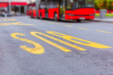 Red public transportation bus on yellow bus stop at street