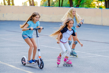 Pretty little girls enjoy themselves riding and competing in the skatepark at warm summer evening