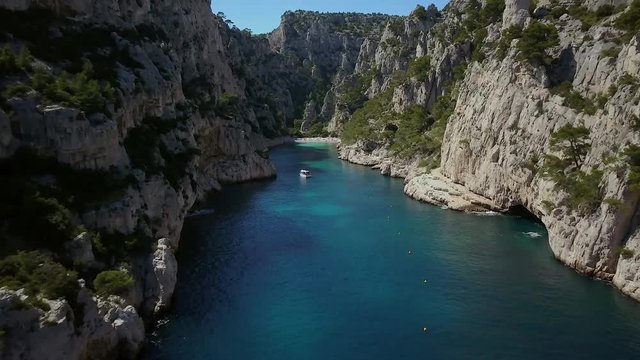 Low-level fly through calanque d'En-Vau. With tourist boat and beachgoers