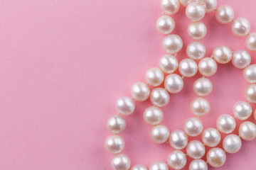 Pearl background with nacreous pearl necklace on pink background - close up macro photo