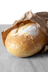 Loaf of white bread in a brown paper bag on grey wood.  Recycle packaging concept.  No plastic waste.