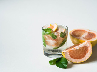 Cocktail or lemonade with mint and grapefruit in glass. Fruit lemonade. White background. Healthy citrus summer drink.