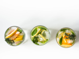 Set summer cold drinks with different citrus and herds in glasses on a white background. Cocktail with grapefruit, orange, lemon and ice isolated