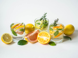 Set summer cold drinks with different citrus and herds in glasses on a white background. Cocktail with grapefruit, orange, lemon and ice isolated