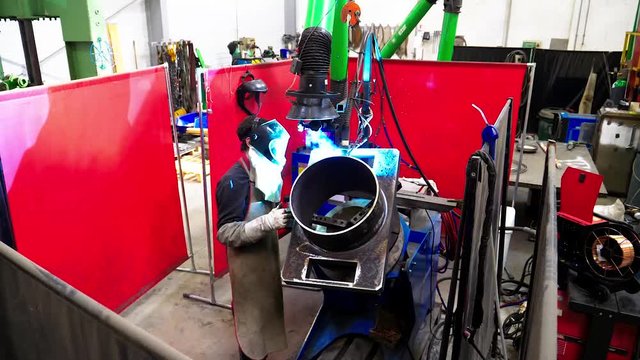 A man worker soldering / welding a stainless steel piece in a factory.

Un ouvrier homme en train de souder une pi&egrave;ce en acier inoxydable.