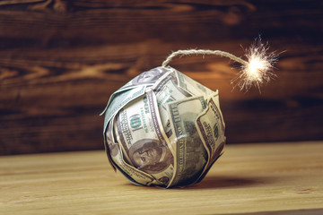 Bomb of money like dynamite, hundred-dollar bills with a burning fuse. Concept of the financial...