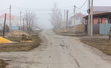 Road in a cottage settlement in the fog