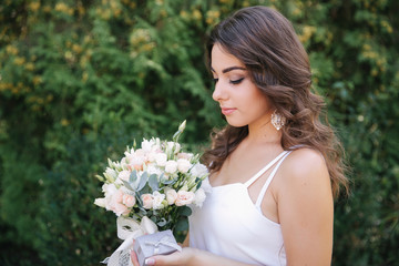 Gorgeous female in white dress slime. Beautiful girl hold a bouquet of flowers in hands