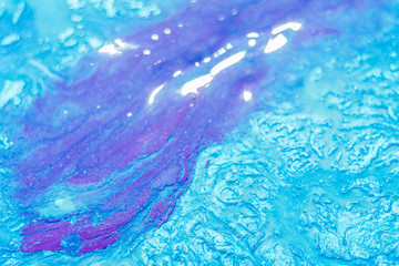 Abstract art background. Purple polish flowing over sky blue textured surface. Beautiful paint with bubbles and sparkling effect.