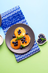 Pancakes served with fresh blueberries on gray plate over geometrical background. Healthy home made breakfast concept