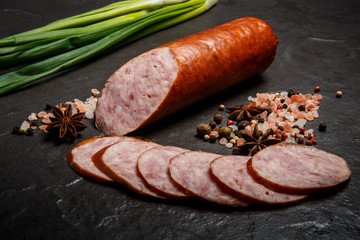 closeup smoked ham sausage with sliced pieces and green onions